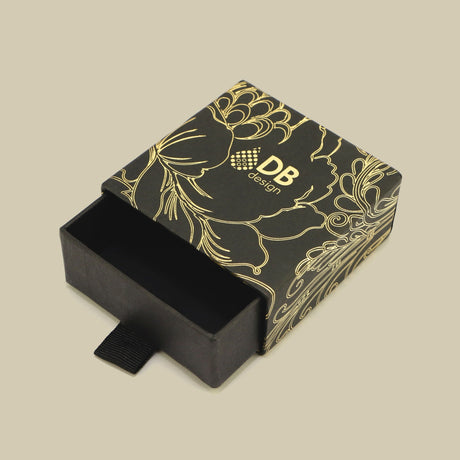 Caixa deslizante com padrão floral dourado e detalhe em fita.